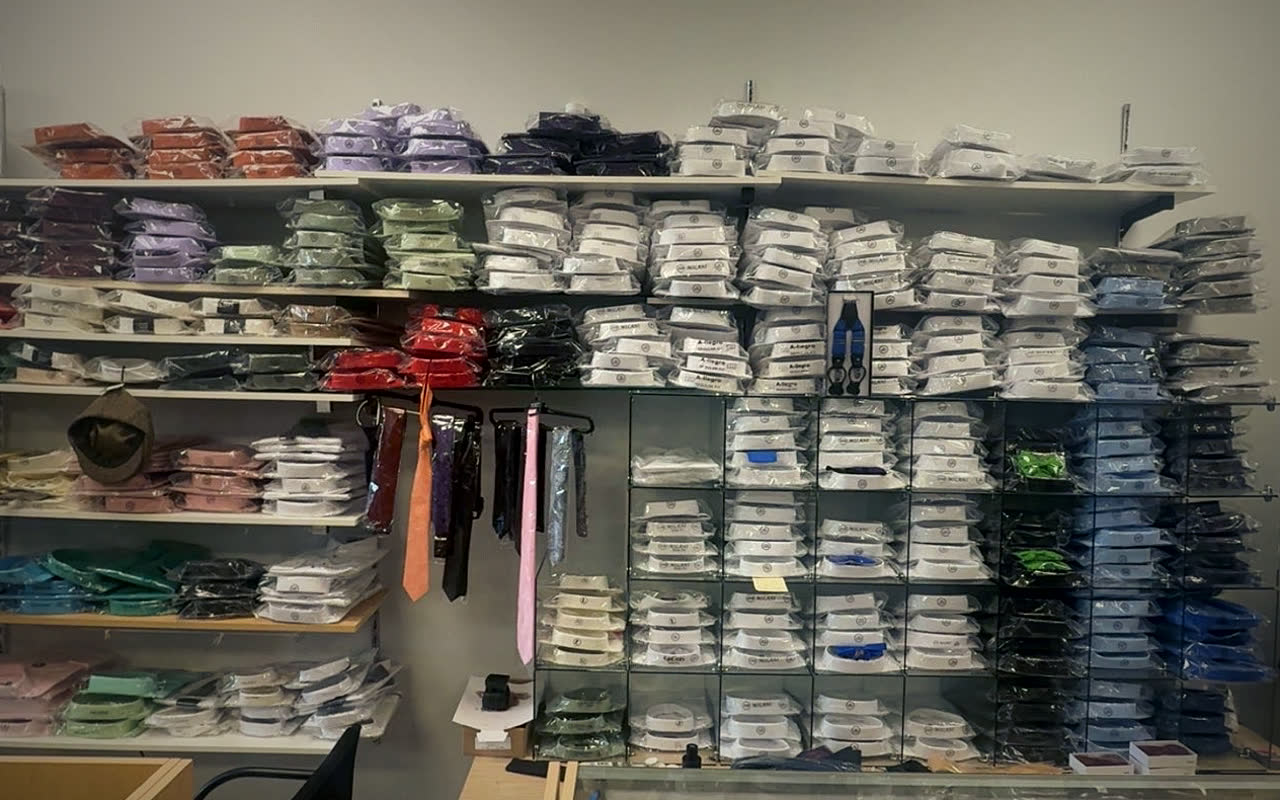 Shelves of folded dress shirts in white, light blue, lavender, pink, mint, red and navy, with a few ties hanging between them