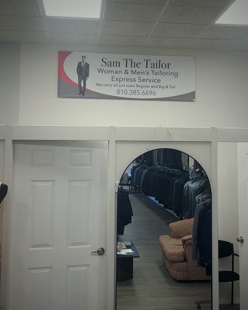 The tailoring room at Mr. Sam Menswear & Tailoring: the Sam The Tailor sign above a fitting mirror and dressing room doors
