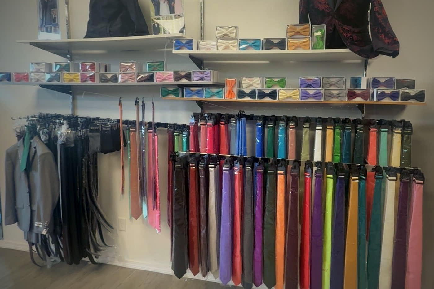 A wall of ties in every color, with boxed bow ties on the shelves above and belts hanging to the left